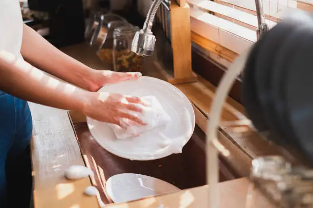 Photo of Close up maid housewife washing cleaning dishes in kitchen