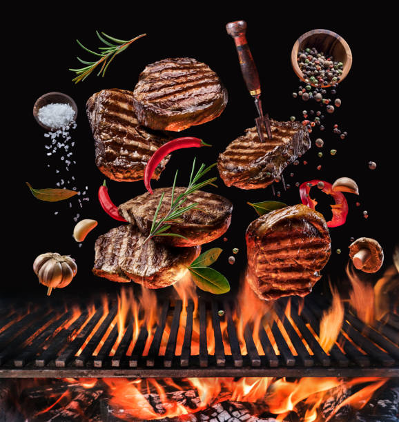 istock Grilled beef steaks and vegetables in motion falling down on open grill.  Conceptual photo of meat or barbeque cooking process. 1209211373
