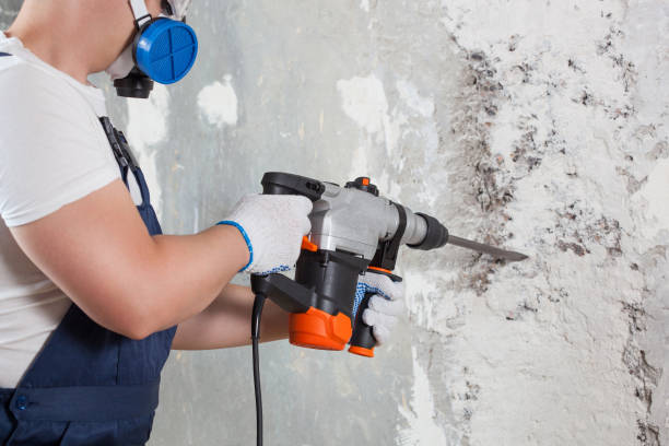 The builder with hammer drill perforator equipment making hole in wall at construction site. Repair work, interior decoration of walls. The builder with hammer drill perforator equipment making hole in wall at construction site. Repair work, interior decoration of walls. holding drill stock pictures, royalty-free photos & images