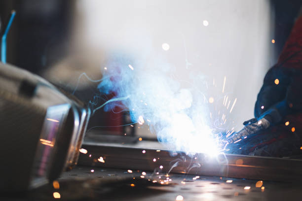 istock Young professional welder grinding and welding metal bars 1209211678
