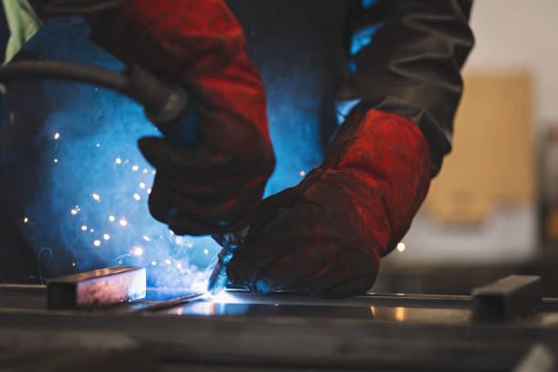 istock Young professional welder grinding and welding metal bars 1209211737