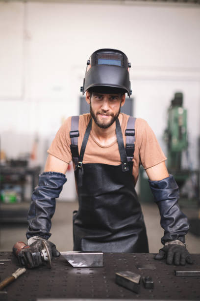 istock Young professional welder grinding and welding metal bars 1209213099