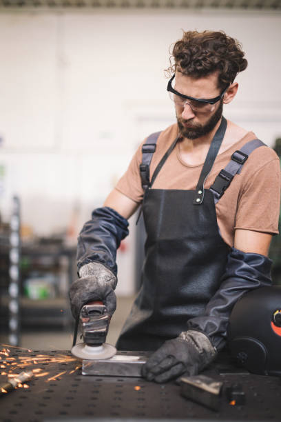 istock Young professional welder grinding and welding metal bars 1209213298
