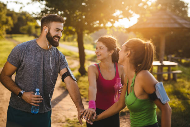 istock Group of runners smiling and stacking hands while standing in woods 1209215973