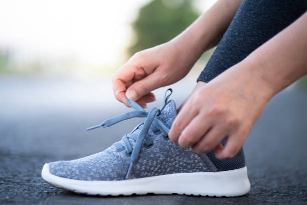 istock Cropped image of hands tying shoelaces on sneaker, running surface background. 1209221388
