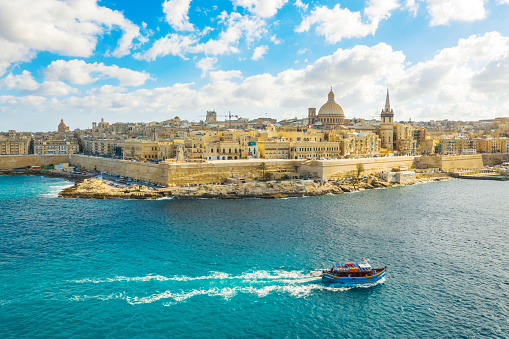 Aerial view of  Valletta city - capital of Malta. Tourist boat in Mediterranean sea. Blue sky