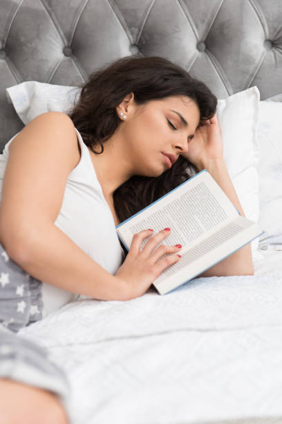 istock Young woman fell asleep in bed while reading a book 1209226646