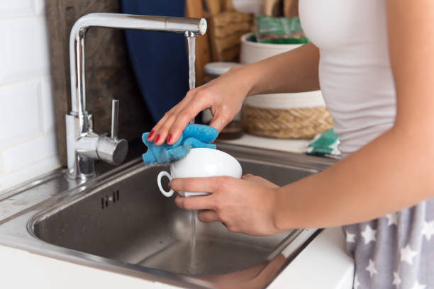 istock Young woman washes dishes in the kitchen 1209228205