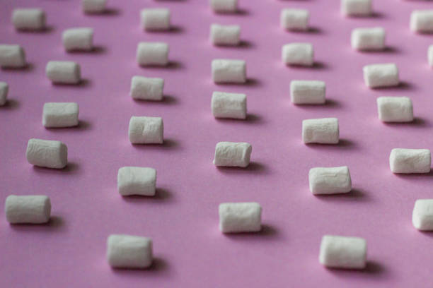 istock White marshmallows pattern on pink paper background. Geometric pattern of white marshmallows on color background. 1209231475