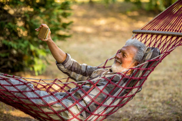 istock Senior Man Lying In Hammock Taking Picture 1209232323