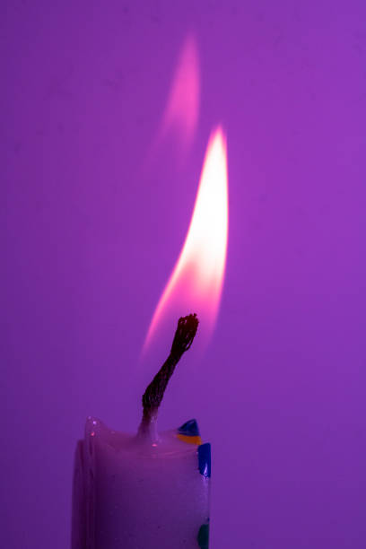 istock A Close Up of a Single Candle Flame and Wick on Coloured Background 1209237266
