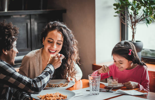 happy african american family eating lunch together at restaurant and having fun - child caribbean black latin american and hispanic ethnicity imagens e fotografias de stock