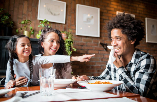 happy african american family eating lunch together at restaurant and having fun - child caribbean black latin american and hispanic ethnicity imagens e fotografias de stock