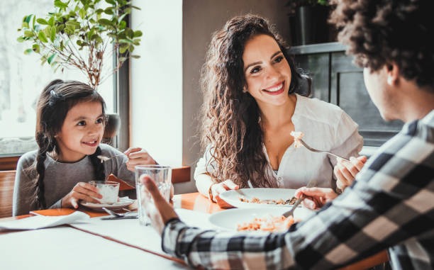 happy african american family eating lunch together at restaurant and having fun - child caribbean black latin american and hispanic ethnicity imagens e fotografias de stock
