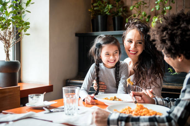 felice famiglia afroamericana che pranza insieme al ristorante e si diverte - child caribbean black latin american and hispanic ethnicity foto e immagini stock