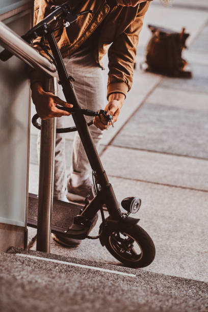 istock Man is parking his electro scooter and ut chain locker on it 1209241429