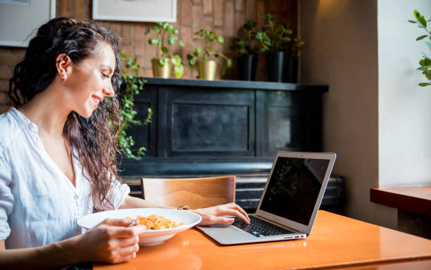 istock Latin young woman working on laptop computer at restaurant, eating break during work 1209242161