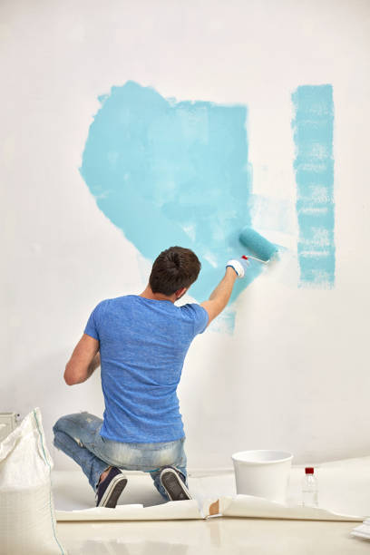 istock smiling man painting wall at home 1209246394