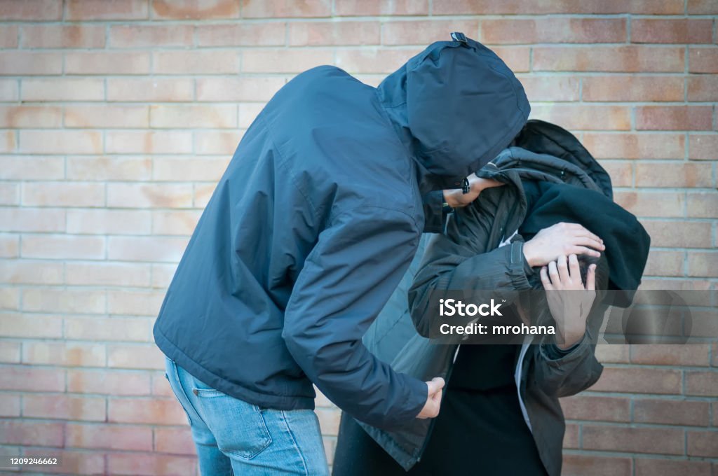 Bullying, aggression and violence scene between two young adult males Bullying, aggression and violence scene between two males, one young adult male punches his peer near a bricks wall Fighting Stock Photo
