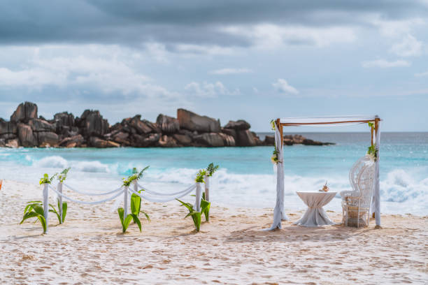 istock Decorated romantic wedding setting with table and chairs on sandy tropical beach in sunset light with moody clouds in background, Seychelles islands. 1209247677