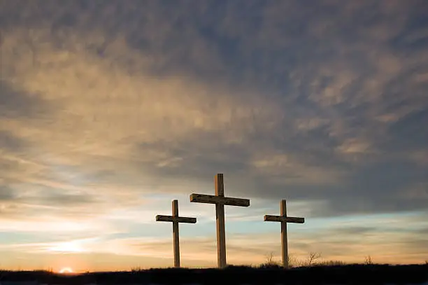 Photo of Three crosses on Good Friday with setting sun and  copy.