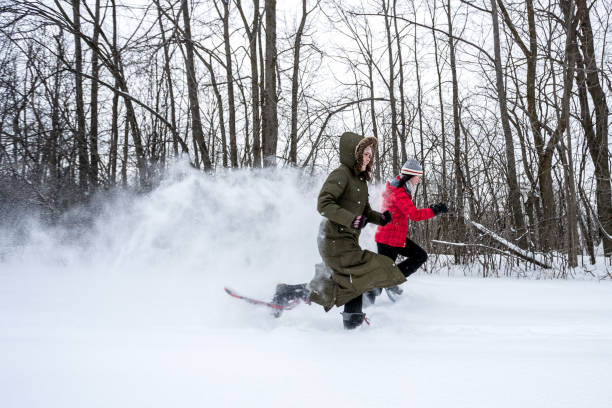 dos mujeres con raquetas de nieve y carreras en el bosque en invierno - winter snowshoeing running snowshoe fotografías e imágenes de stock