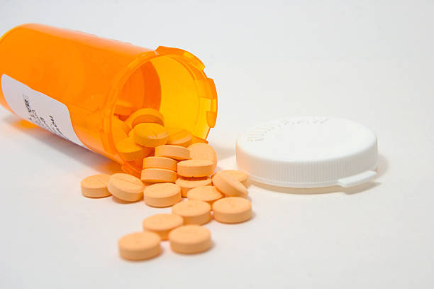 A bottle of pills spilled from a prescription bottle on a white surface and backgroundClick here to see more of my pill photographs!