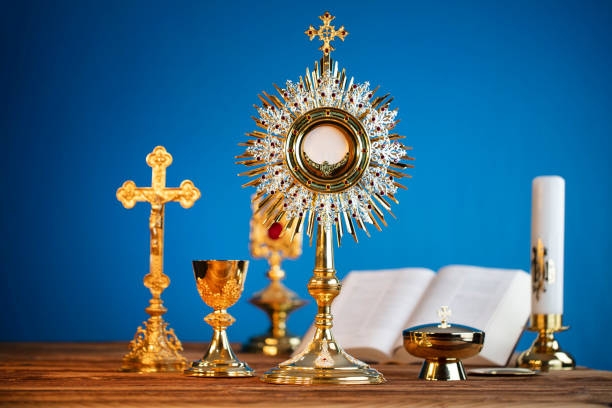 Catholic religion concept. Catholic symbols composition. The Cross, monstrance,  Holy Bible and golden chalice on the altar. Blue background. liturgy photos stock pictures, royalty-free photos & images