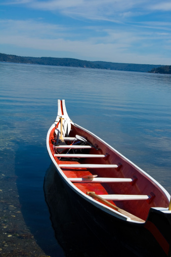A Native American, or First Nation, hand made cedar canoe beached on a calm bay.