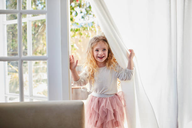 istock Cute little girl smiling while looking through patio doors at home 1209250376