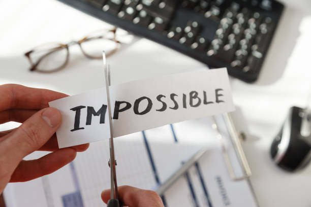 istock Businessman hands cutting the word impossible, letters im so it become possible 1209250677
