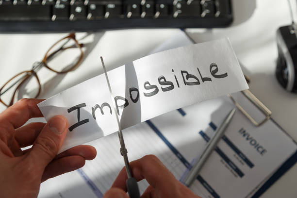 istock Businessman cutting the word impossible, letters im so it become possible 1209250686