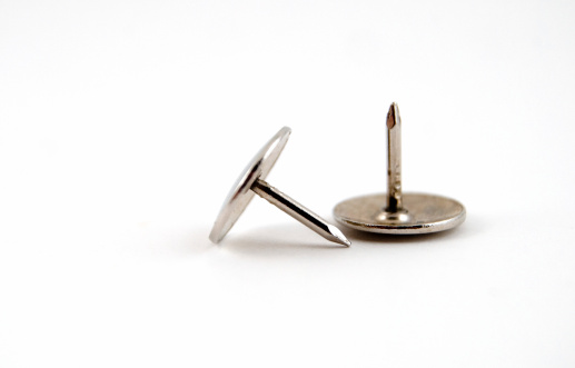 Two metal ... silver ... thumbtacks on a white background with copy space.