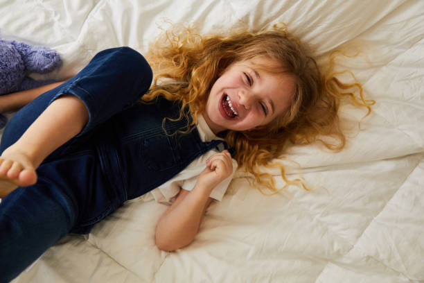 istock Little girl laughing while lying on her bed at home 1209257260