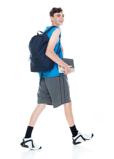 istock Caucasian boys university student walking in front of white background wearing backpack and holding textbook and using sports ball 1209263446
