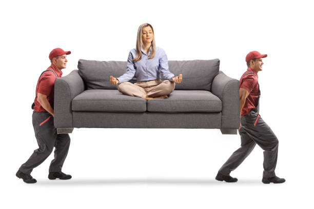 istock Young woman meditating on a sofa and two male workers carrying the sofa 1209265228