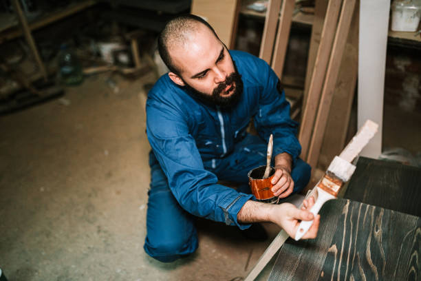 istock Carpenter painting wood in workshop 1209265391