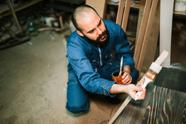 istock Carpenter painting wood in workshop 1209265404