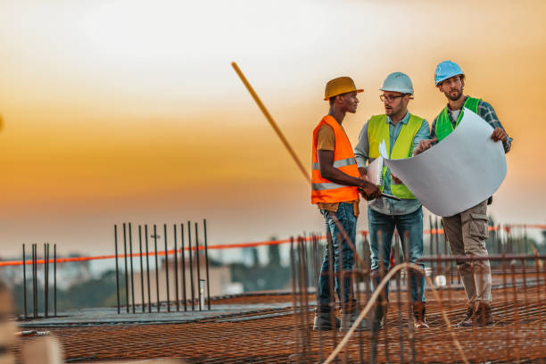 istock Male building contractor giving instructions to group of workers on construction site 1209265474