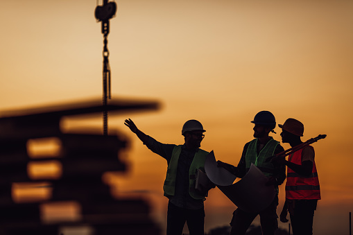 Silhouette of Survey Engineer and construction team working at site over blurred industry background with Light fair Film Grain effect