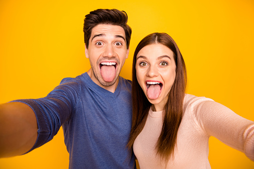 Close up photo of two people married students bloggers relax rest make, selfie fool grimace wear blue pink pullover isolated over yellow color background