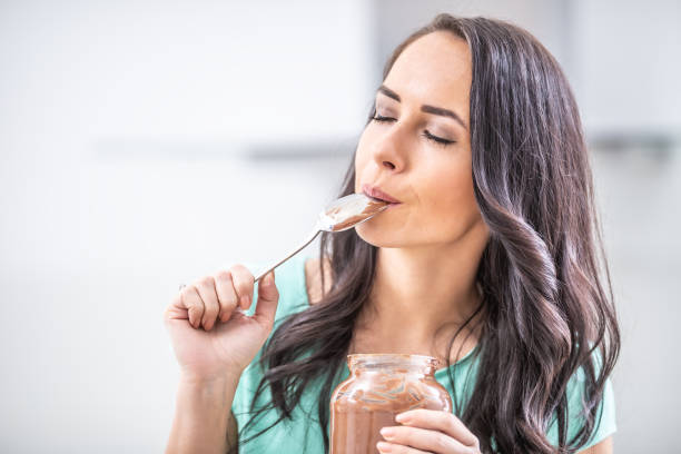 istock Young beautiful woman enjoys emotionally chocolate or hazelnuts cream. 1209267635