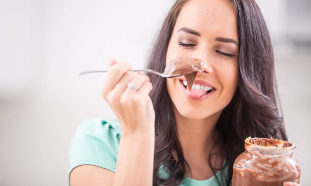 istock Young beautiful woman enjoys emotionally chocolate or hazelnuts cream. 1209267676