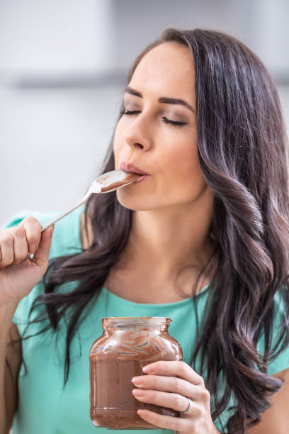 istock Young beautiful woman enjoys emotionally chocolate or hazelnuts cream. 1209267698