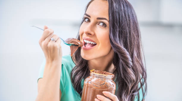 istock Young beautiful woman enjoys emotionally chocolate or hazelnuts cream. 1209267716