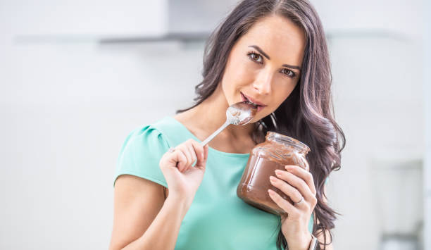 istock Young beautiful woman enjoys emotionally chocolate or hazelnuts cream. 1209268241