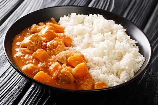 African stew Domoda with peanuts cooked with chicken pumpkin and served with rice close-up in a plate on the table. horizontal.