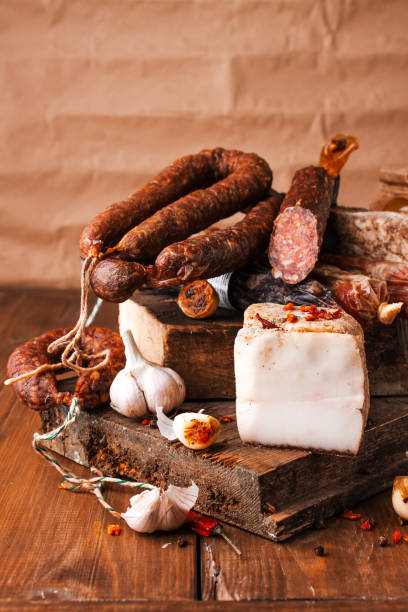 salsiccia di maiale affumicata. costolette per bambini, pane bianco, pane di mais, fagioli al forno, insalata di patate, ecc. varie carni tradizionali affumicate e barbecue. selezione di salumi salsicce decorate con aglio e pepe - cooked food variation black pudding foto e immagini stock