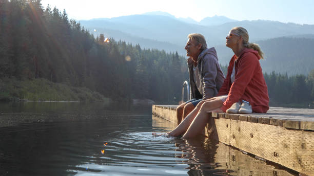 成熟したカップルは木製の桟橋でリラックスし、湖を見渡す - 11250 ストックフォトと画像