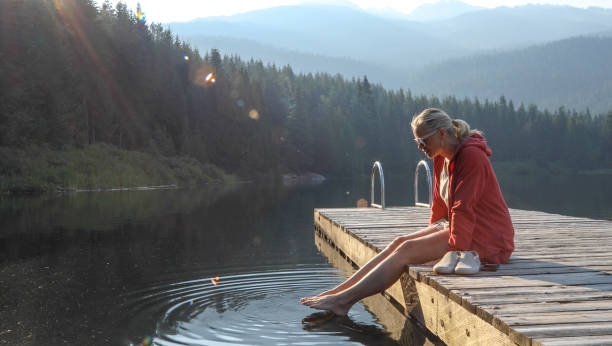la donna matura si rilassa sul molo di legno, si affaccia sul lago - 11242 foto e immagini stock